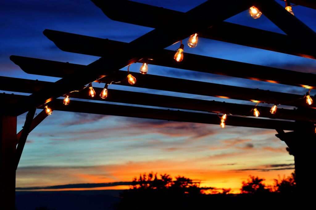 Outdoor lighting on a pergola at sunset.